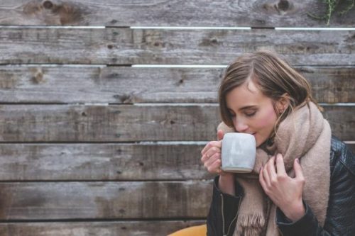 外でホットドリンクを飲む女性