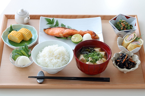 ご飯と味噌汁、鮭、副菜が乗った食卓