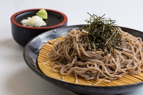 ざるを乗せた深めの器に盛り付けられた蕎麦